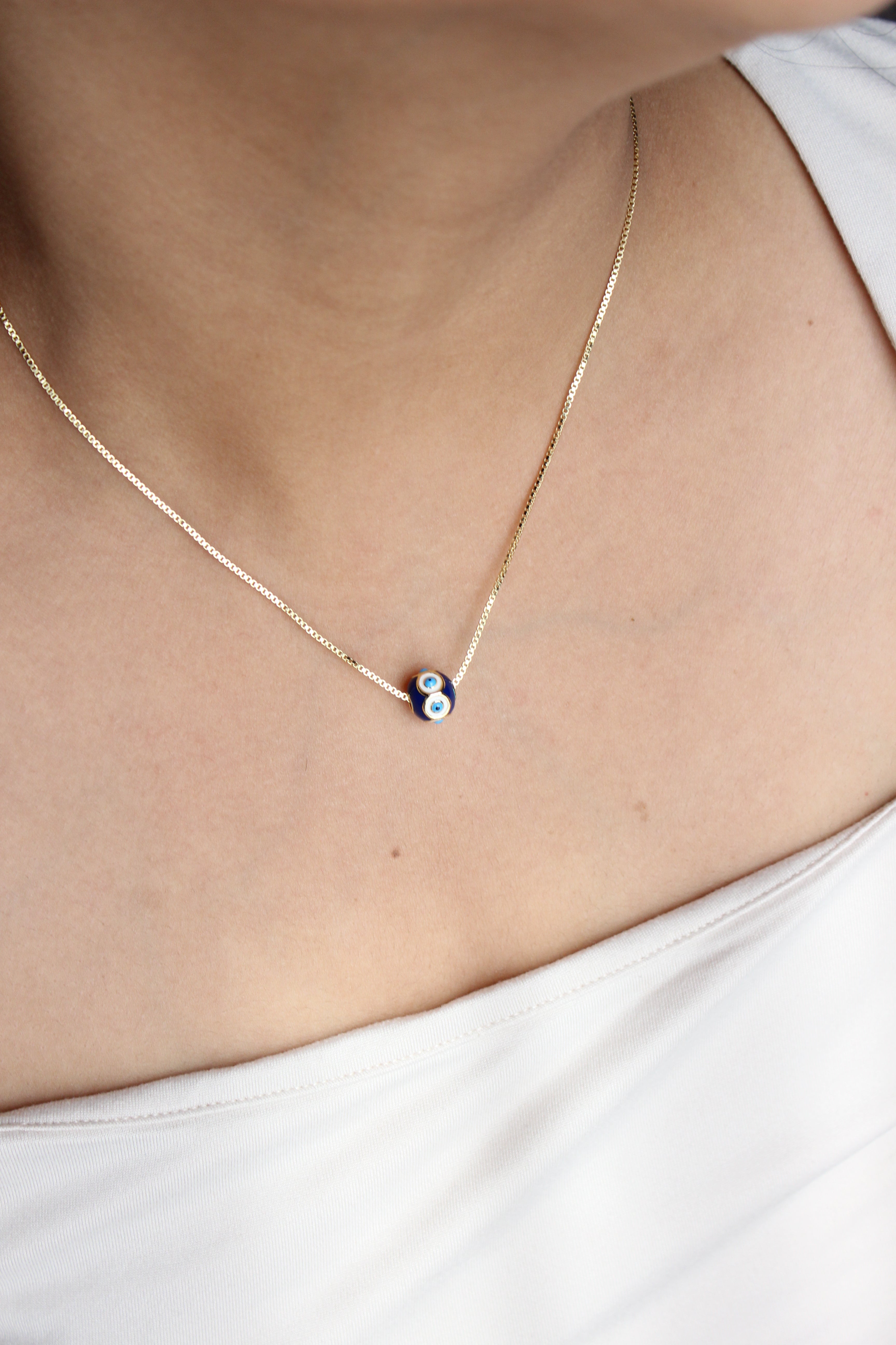 Evil Eye Gem Pendant Necklace on a model wearing a white top