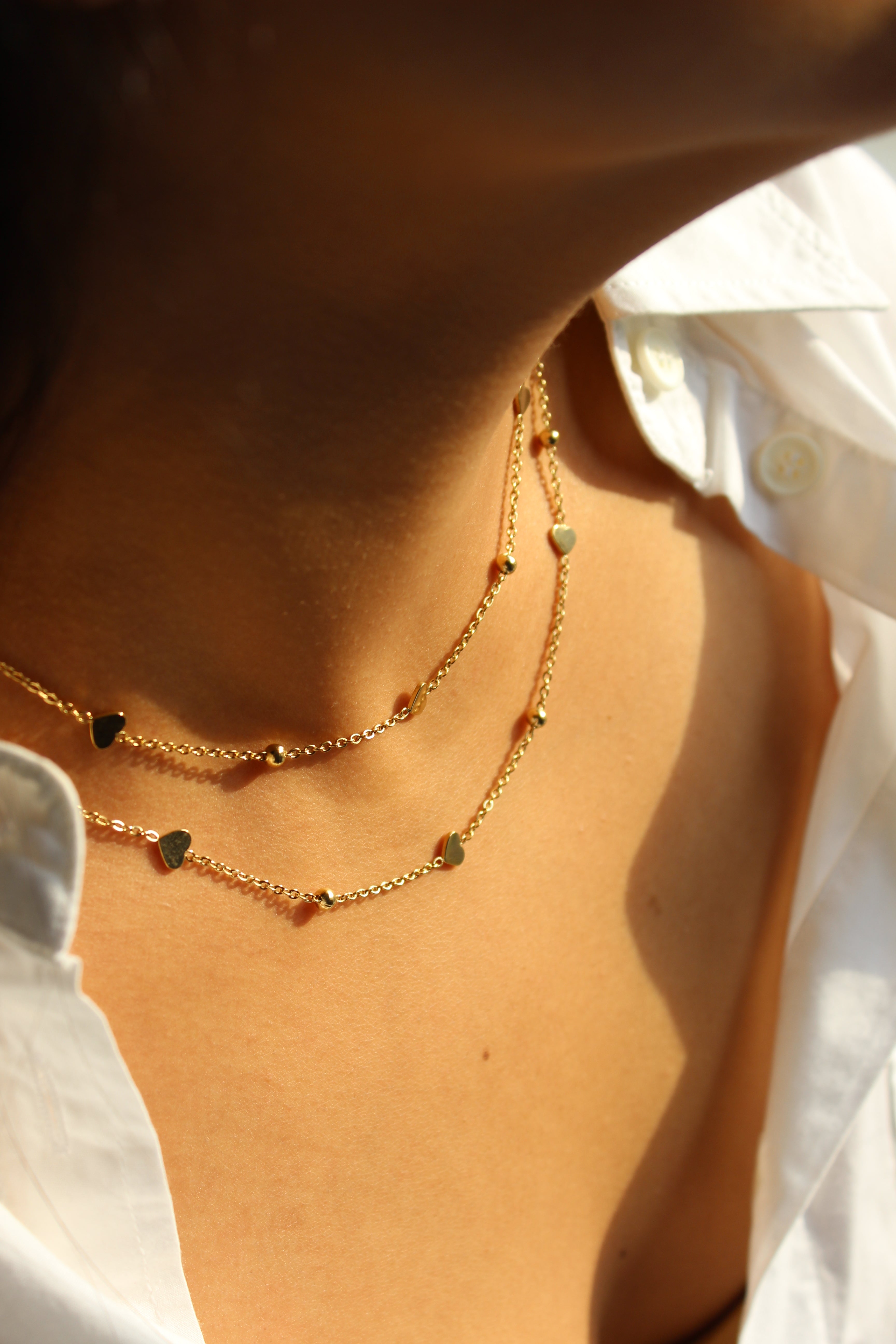 LoveDots Layered Necklace on a model's neck against a white shirt background