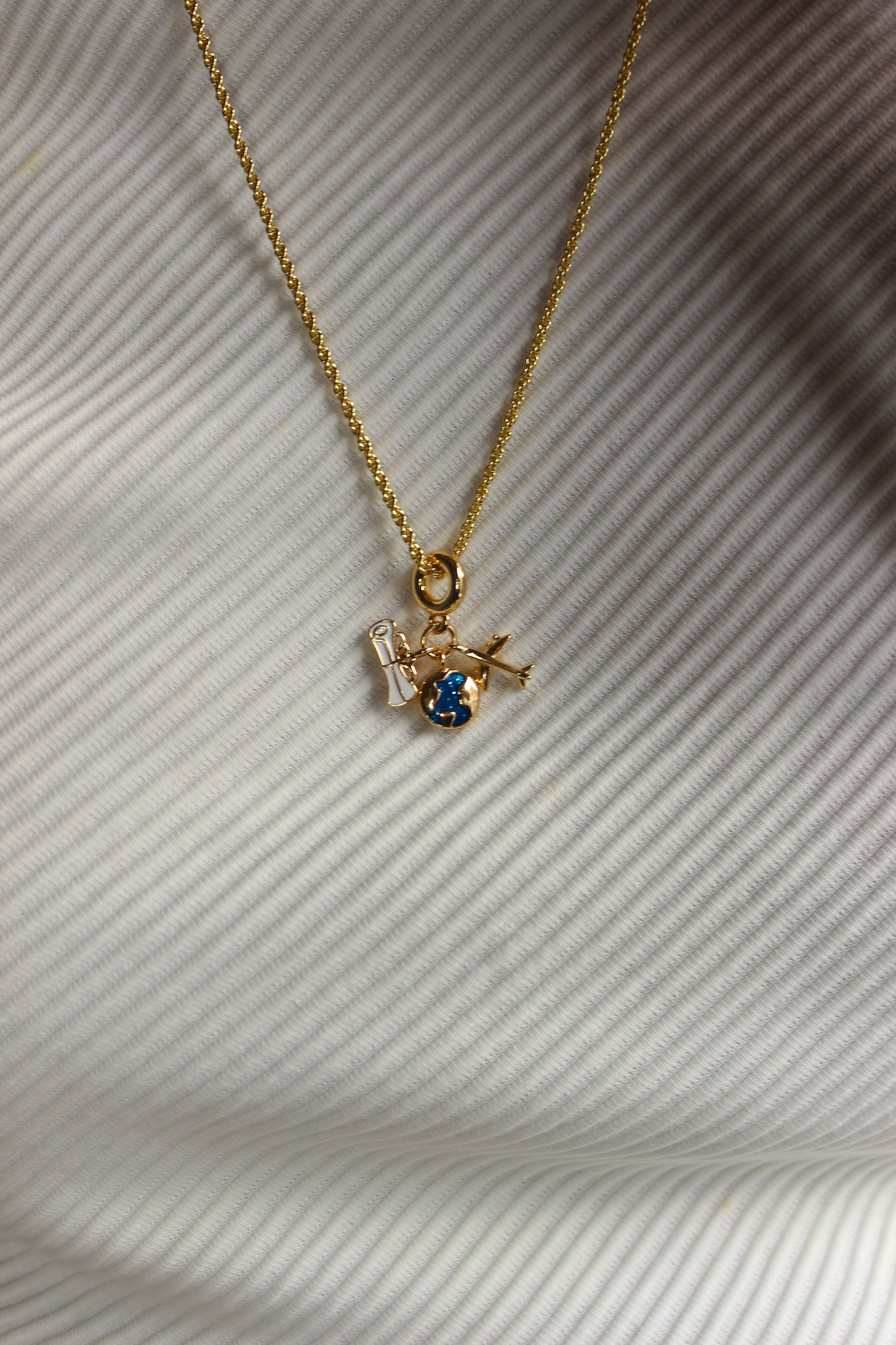 Jet Set Dream Charm Necklace on a textured white surface