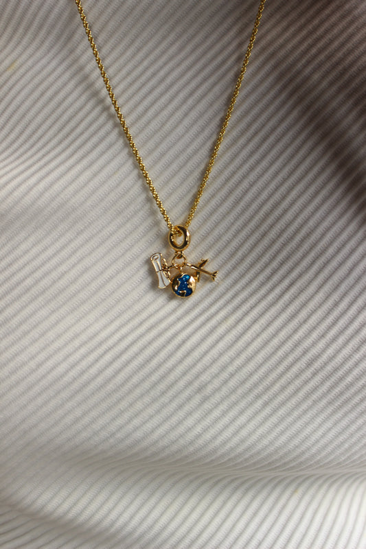 Jet Set Dream Charm Necklace on a textured white surface