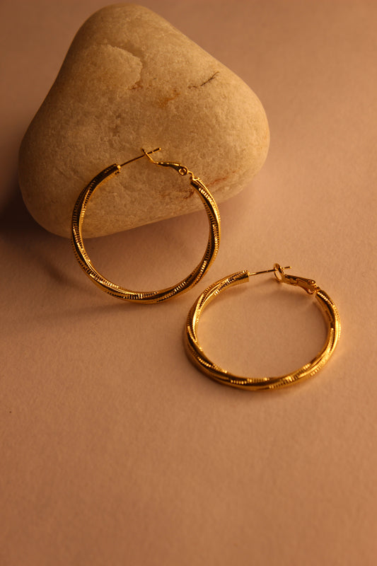 Twistline Hoop Earrings on a beige stone surface