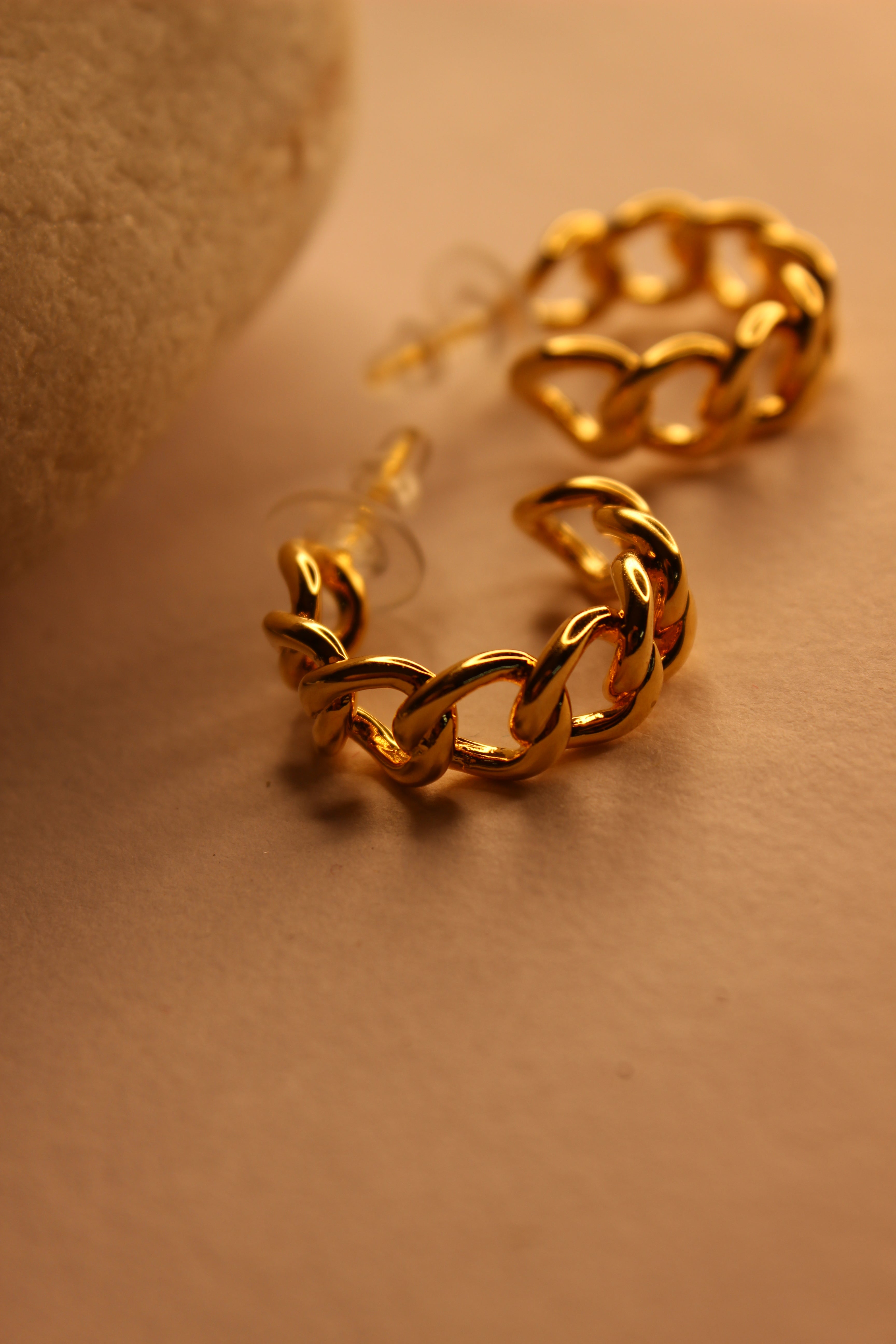 Gold chain-style Tied in Gold Hoop Earrings on a beige background