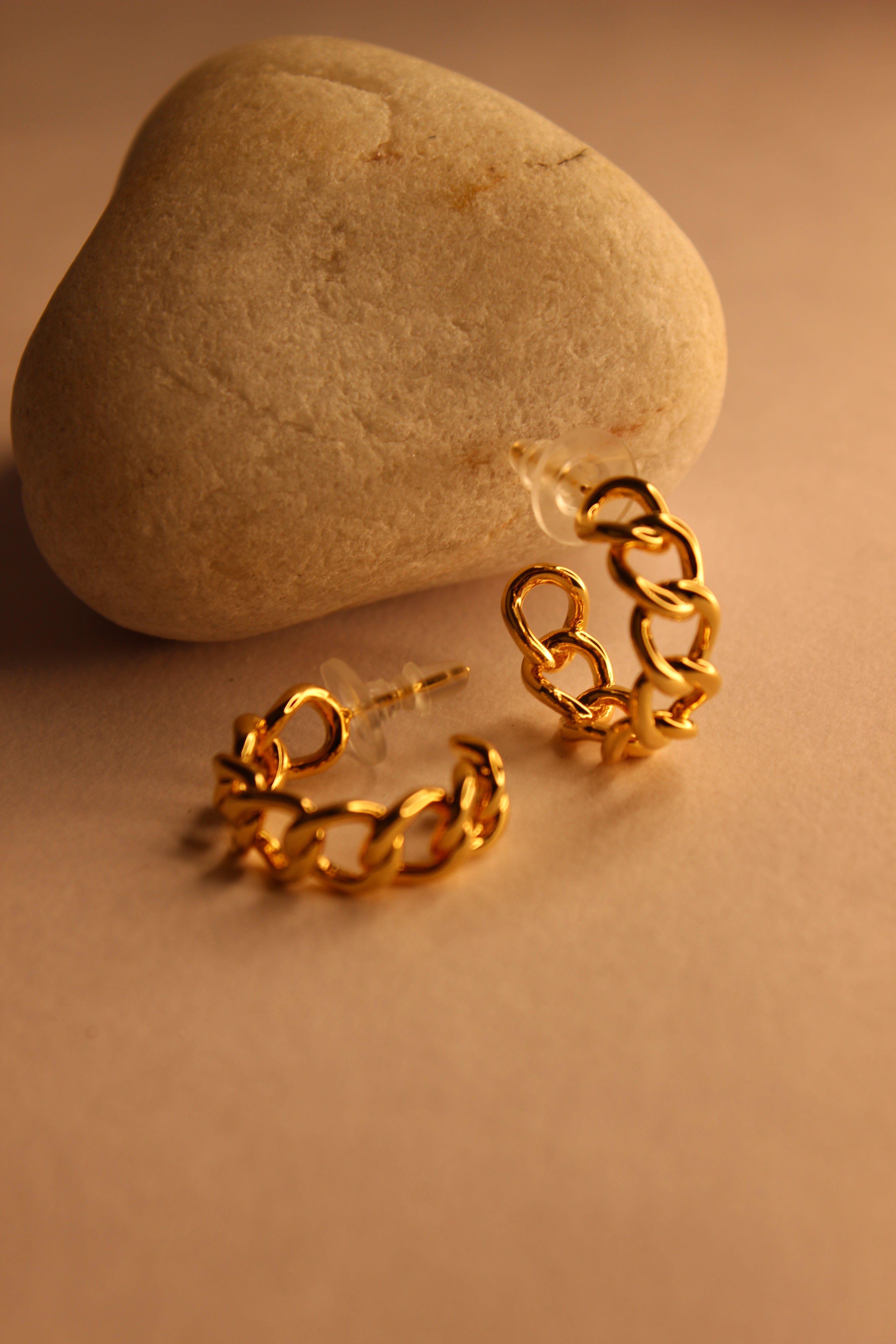 Tied in Gold Hoop Earrings on a stone surface with a warm brown background