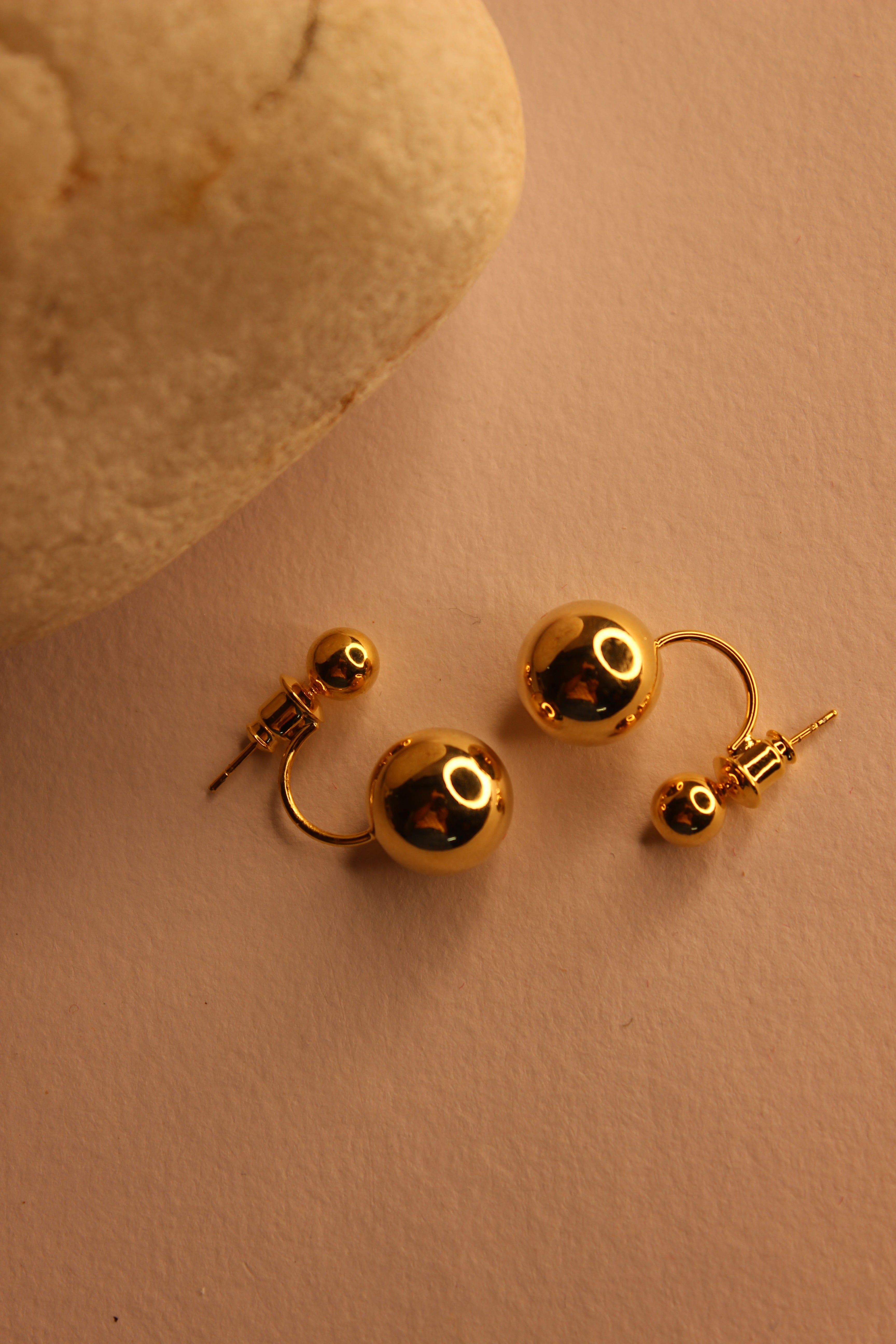 Velisse Stud Earrings on a beige yellow surface