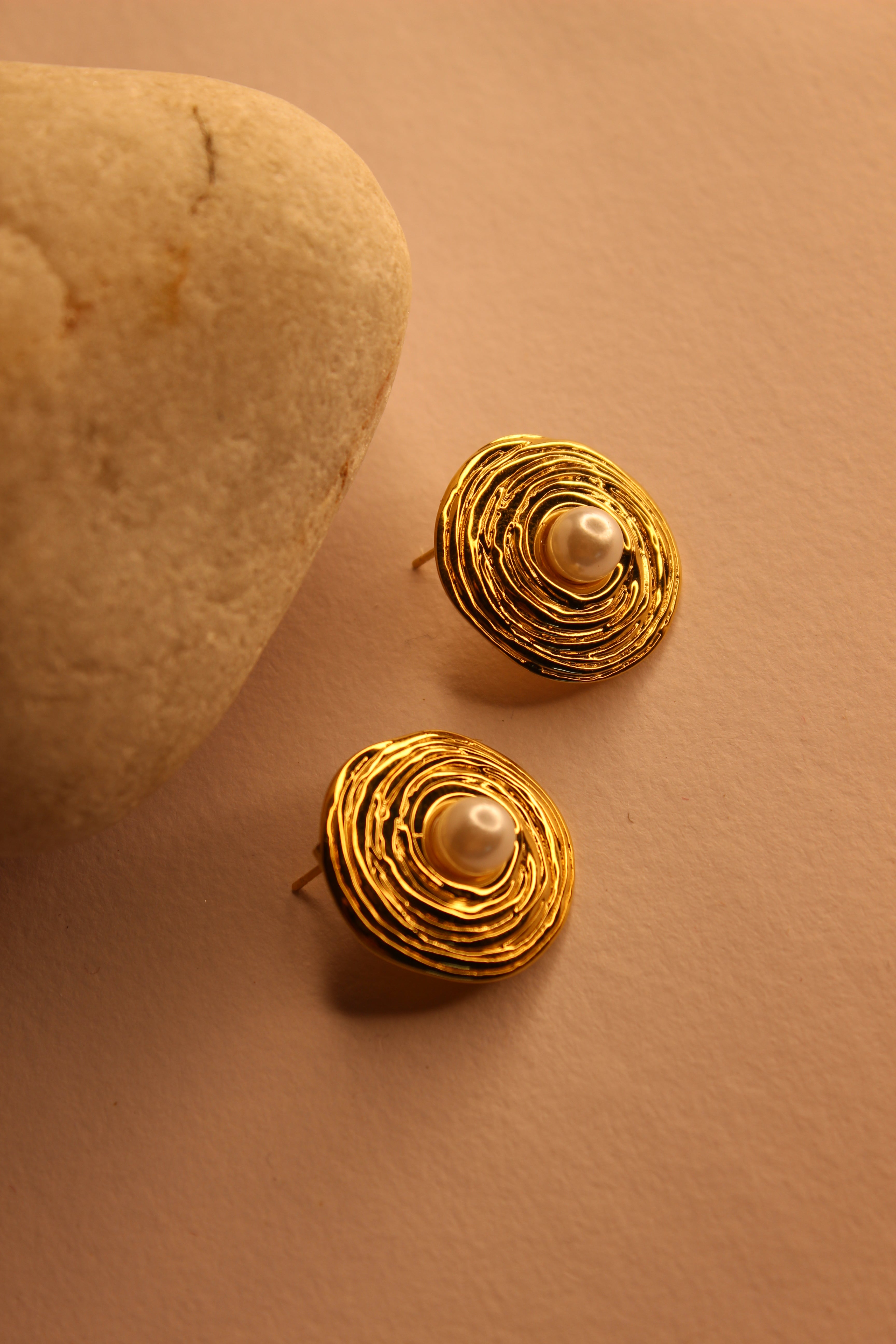 Amara Stud Earrings with pearl centers on a beige background