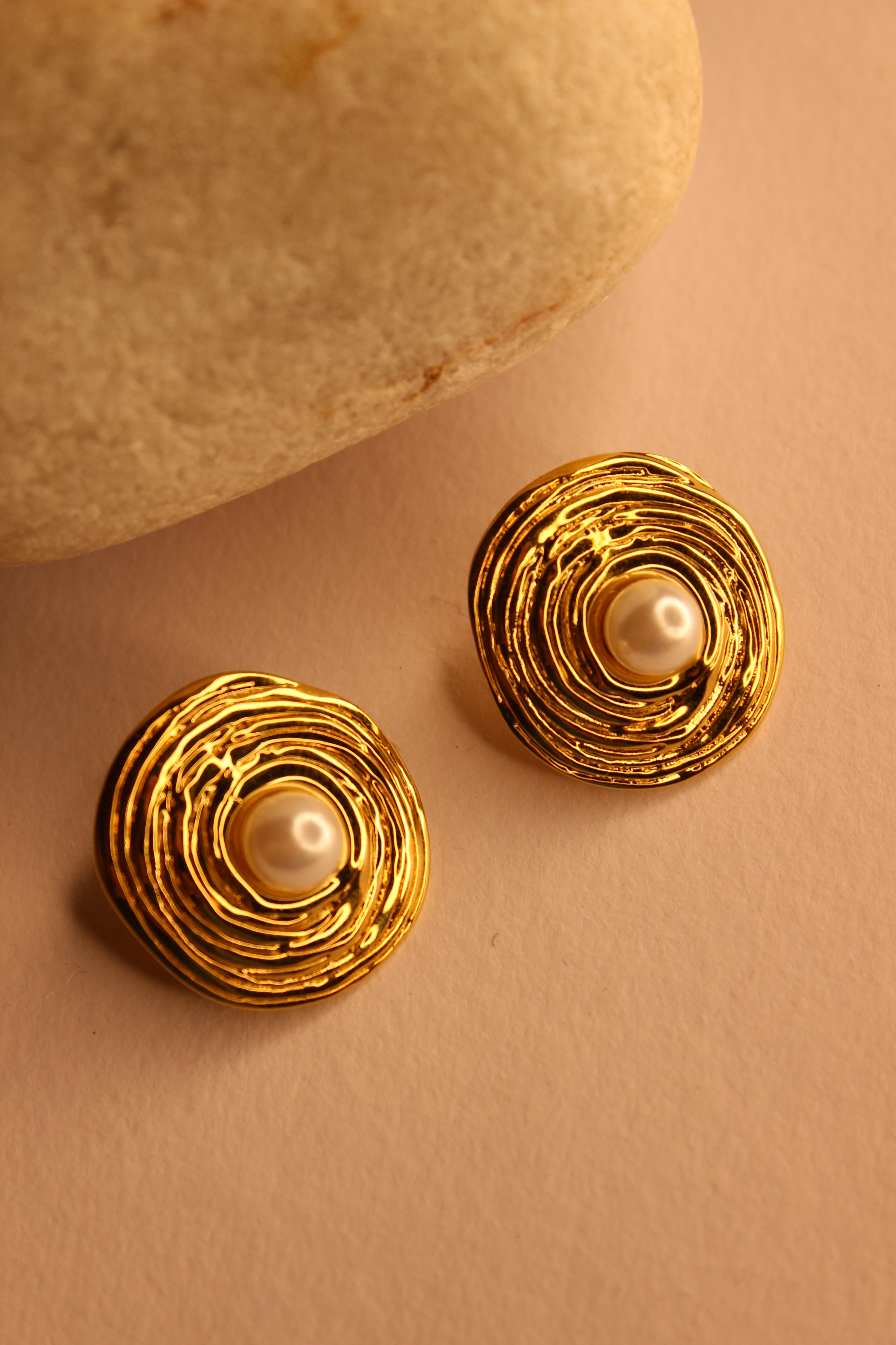 Amara Stud Earrings with pearl centers on a beige background