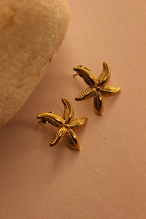 Solstar Stud Earrings on a beige background