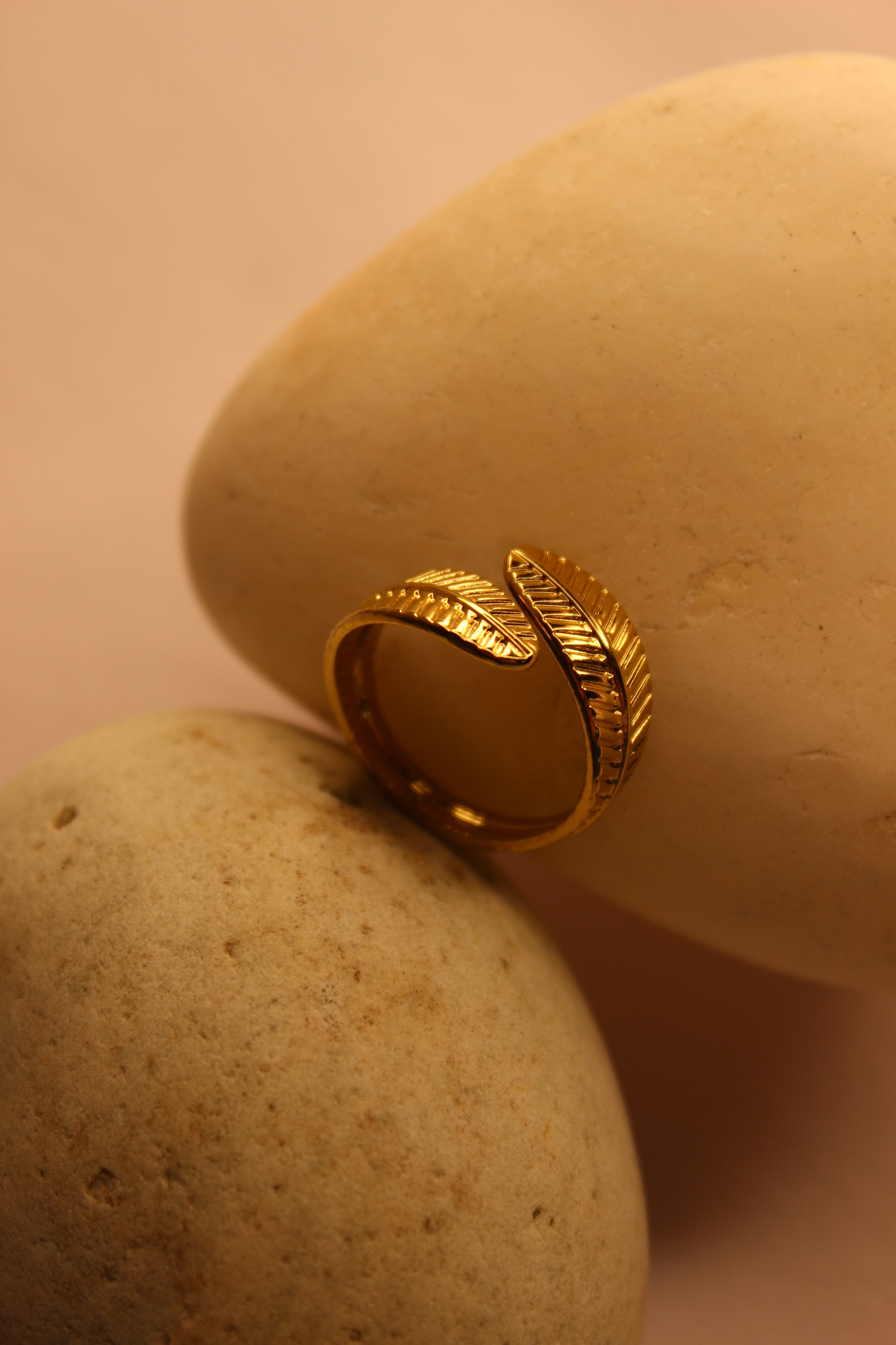 Adara Ring with leaf design on a beige stone surface