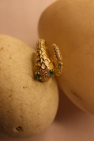 Nysa Ring with green gemstones on a beige stone surface