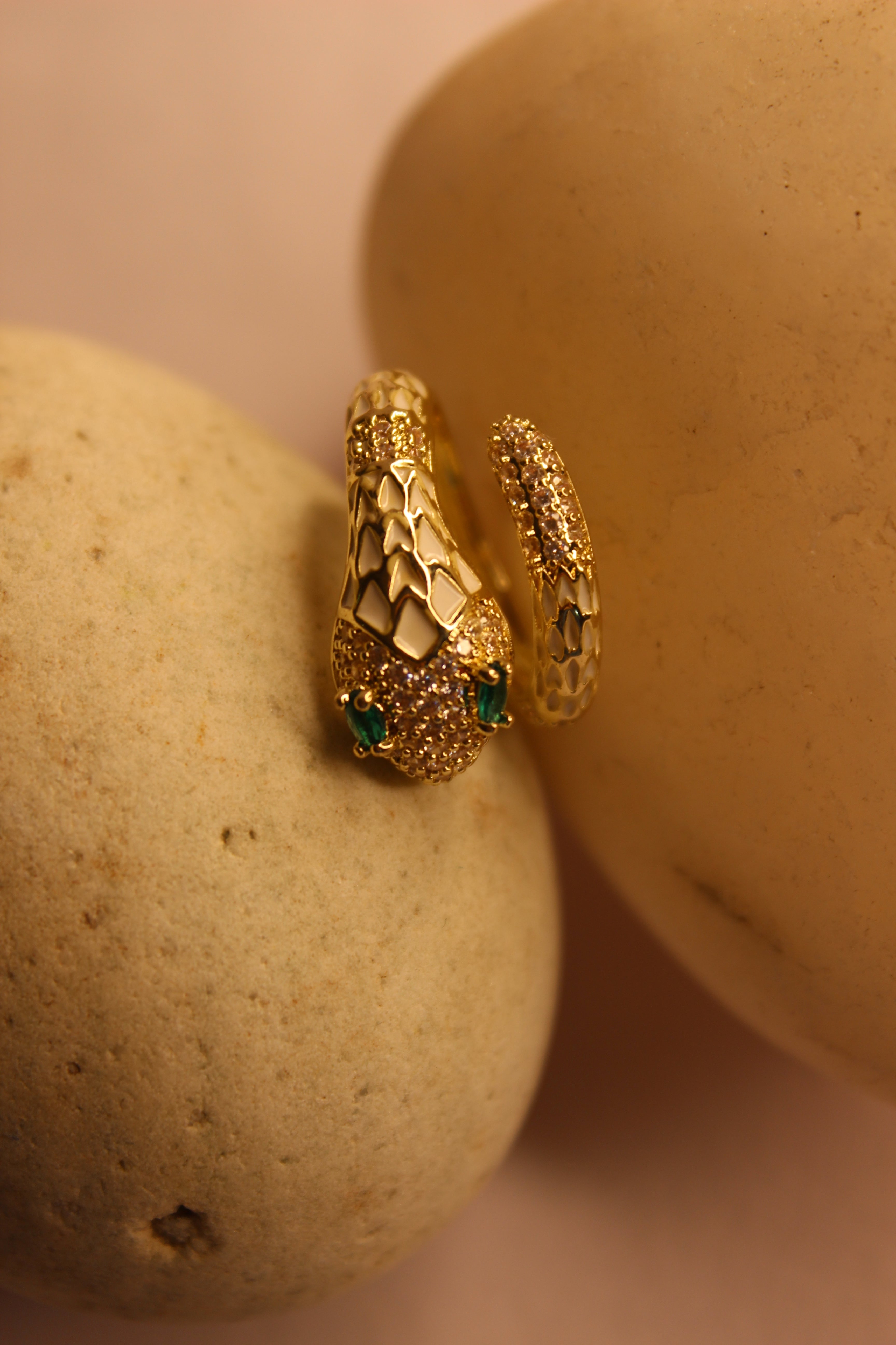 Nysa Ring with green gemstones on a beige stone surface