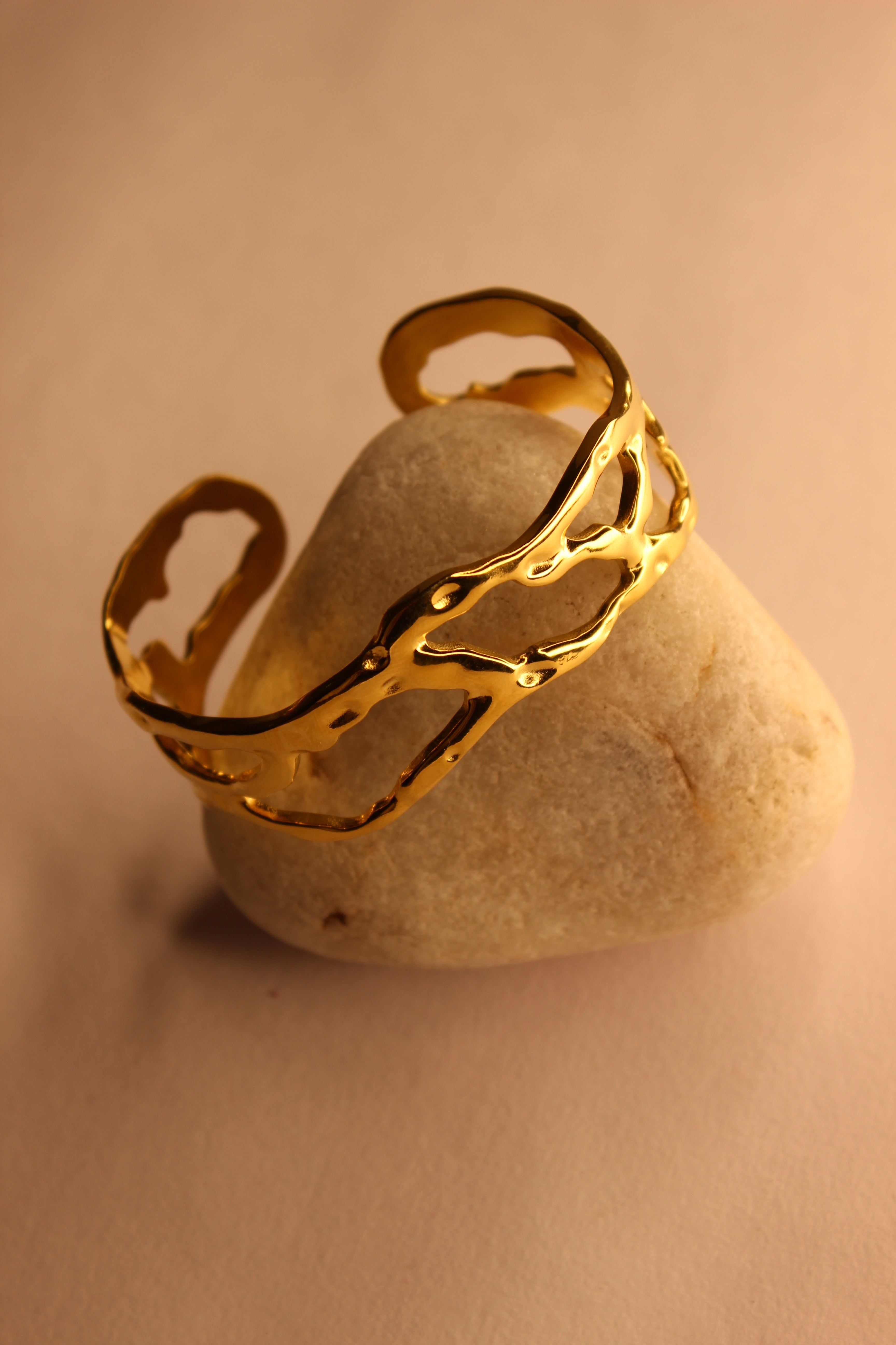 Orra Cuff Bracelet on a stone with a beige background