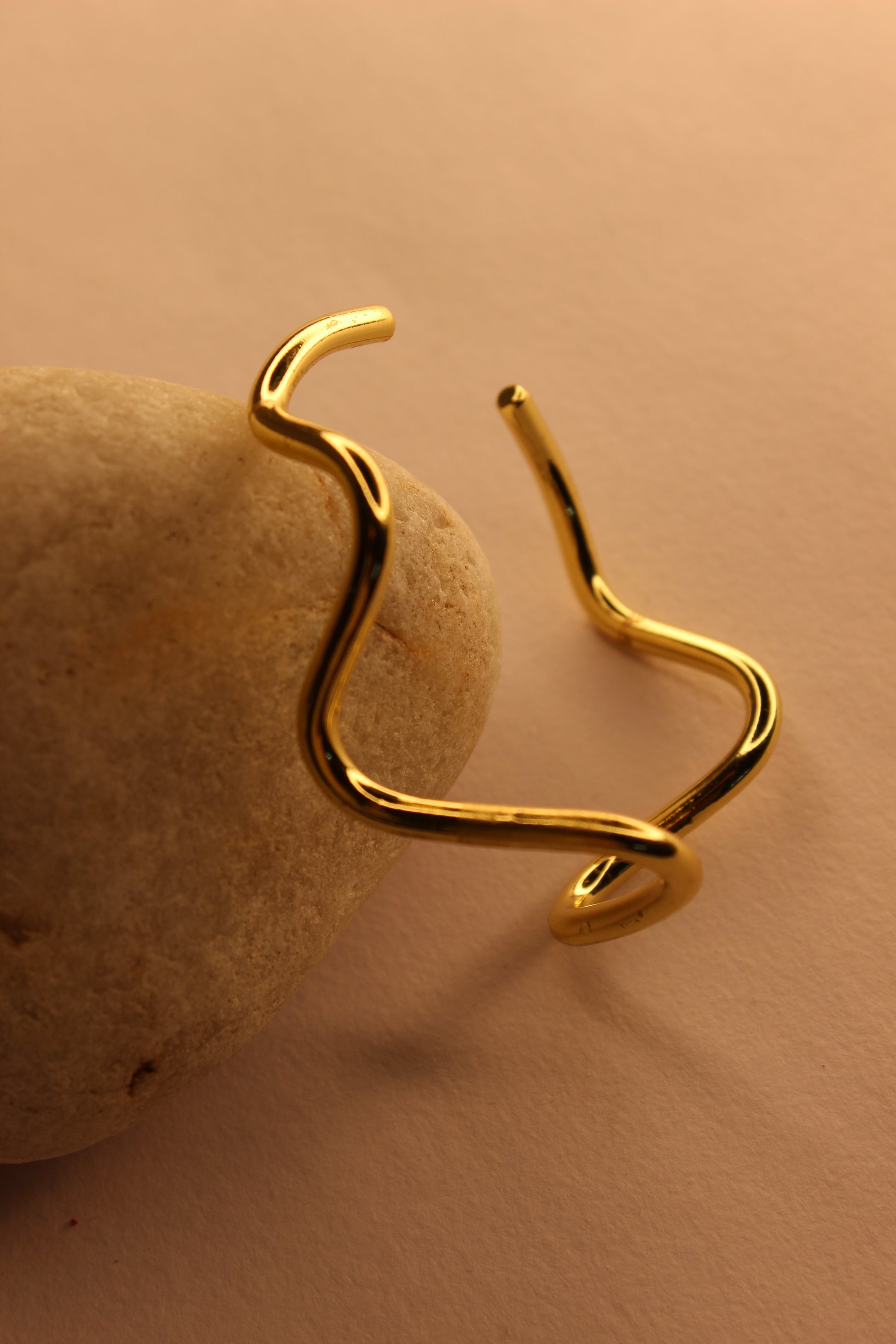 Drift Cuff Bracelet on a beige stone against a beige background