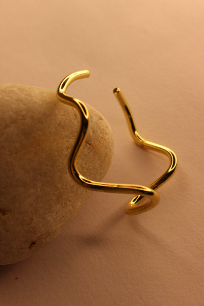 Drift Cuff Bracelet on a beige stone against a beige background
