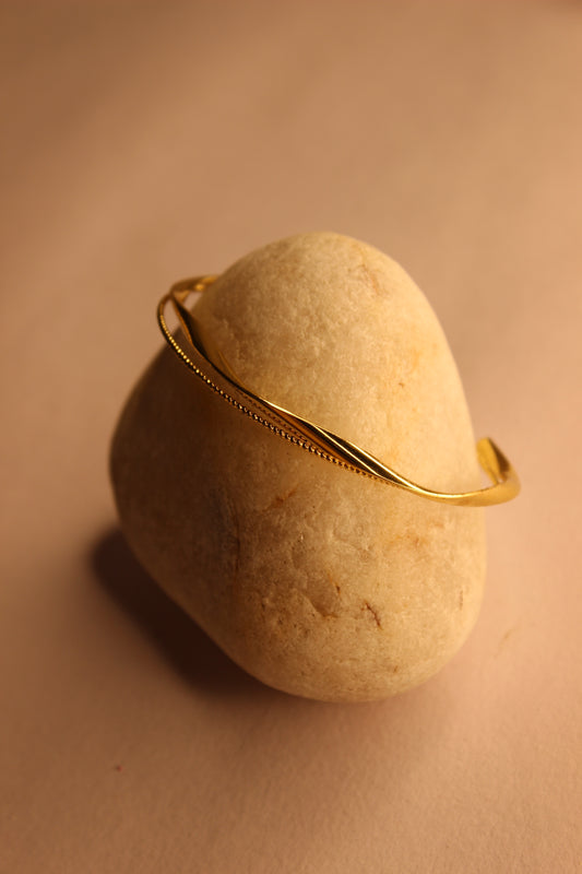 Auriin Cuff Bracelet on a beige stone with a soft focus background