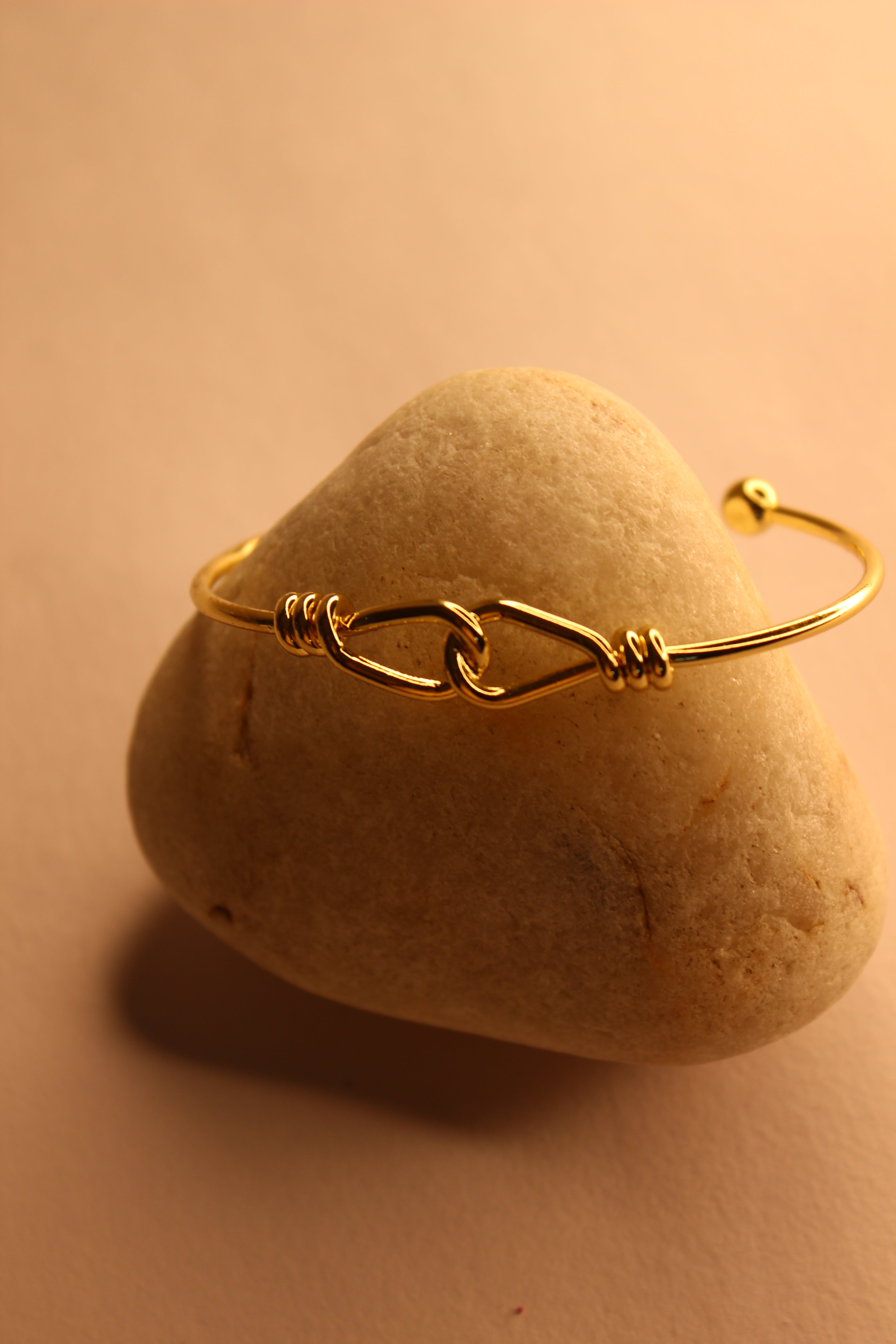 Tether Cuff Bracelet on a heart-shaped stone with a soft yellow background