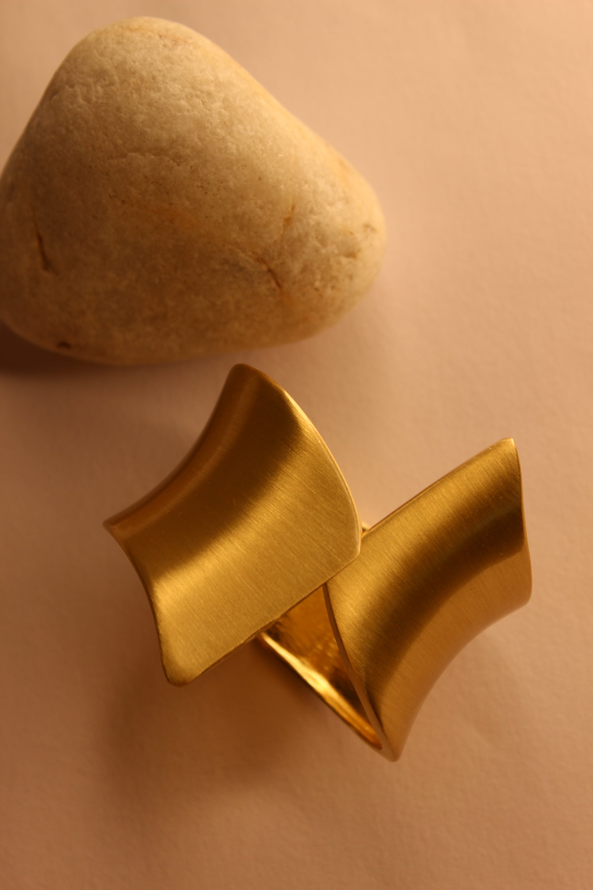 Arcus Bracelet next to a stone on a beige background
