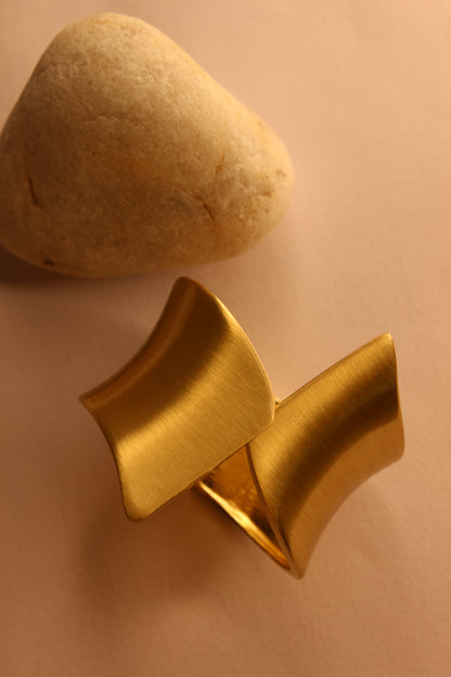 Arcus Bracelet next to a stone on a beige background