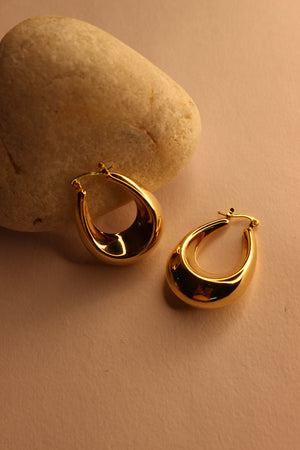 Solara Hoop Earrings on a textured beige surface