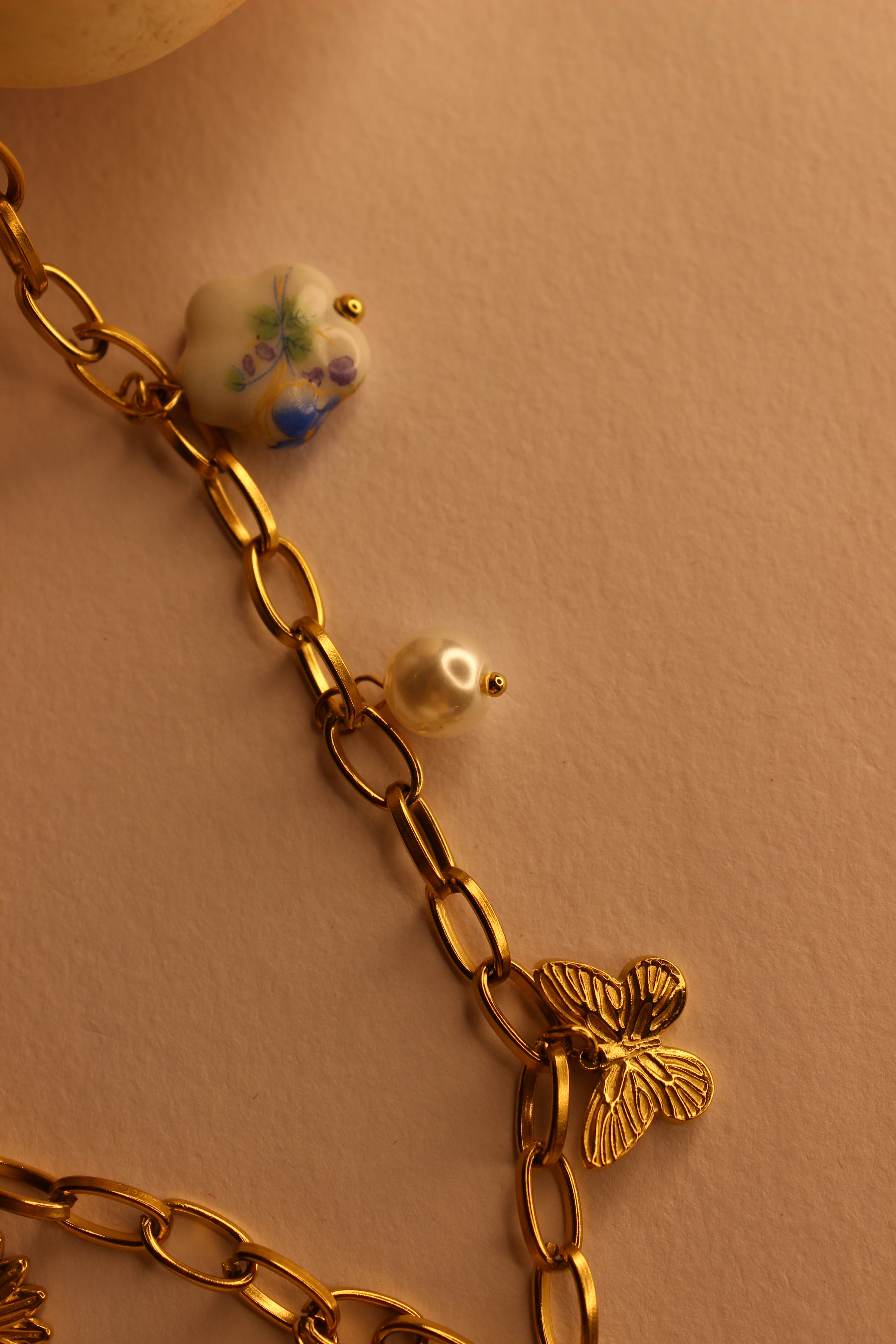 Hearts in Bloom Charms Necklace with decorative stones on a beige background