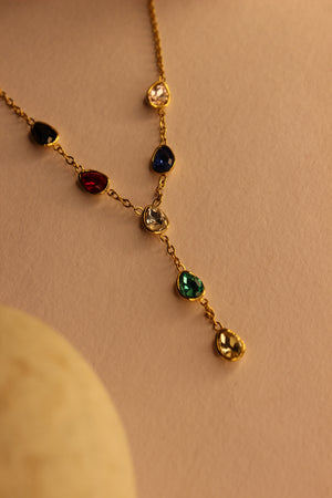 Prism Drop Necklace with colored gemstones on a beige background