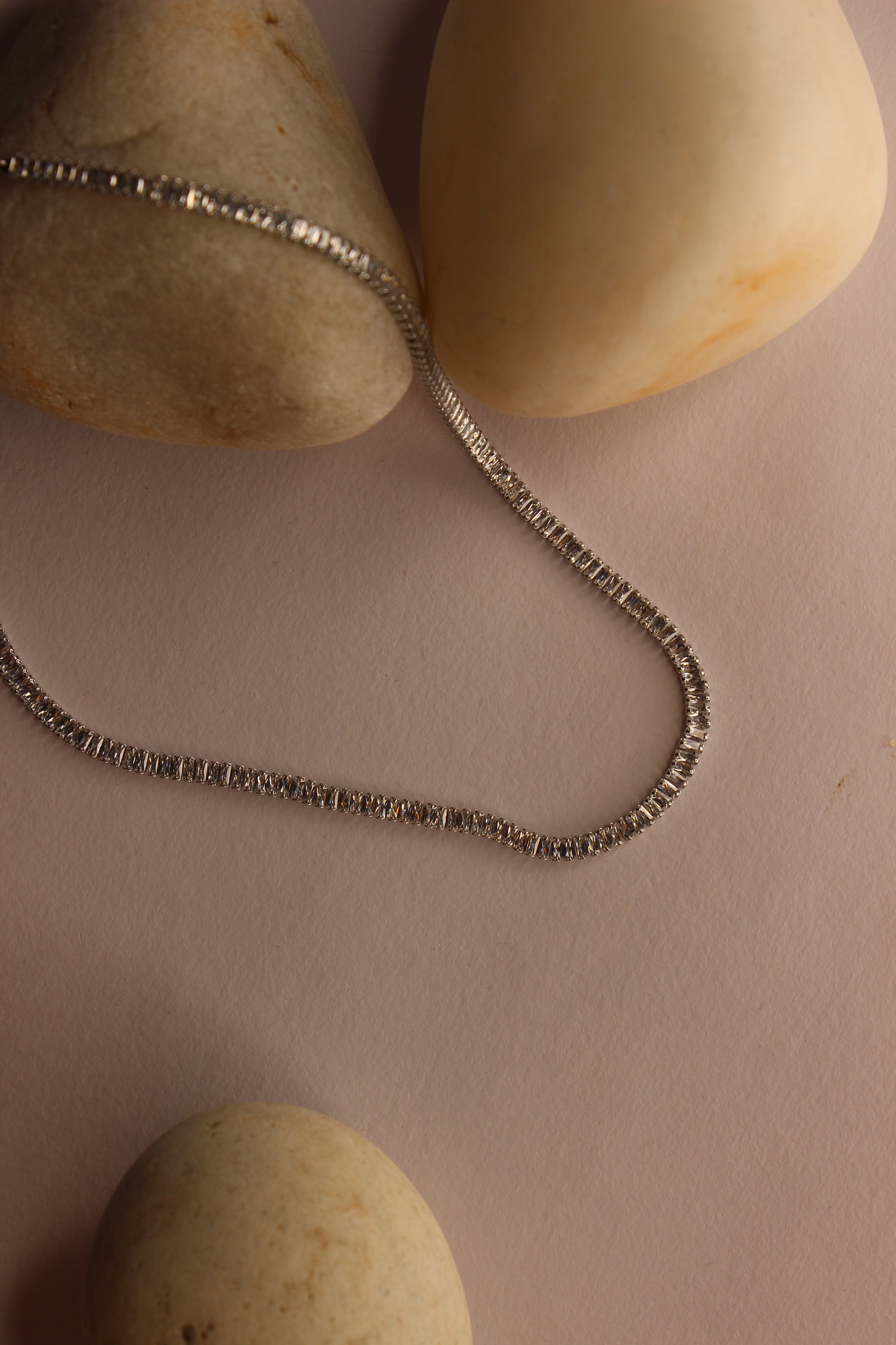 Twilite Necklace on a beige surface with stones