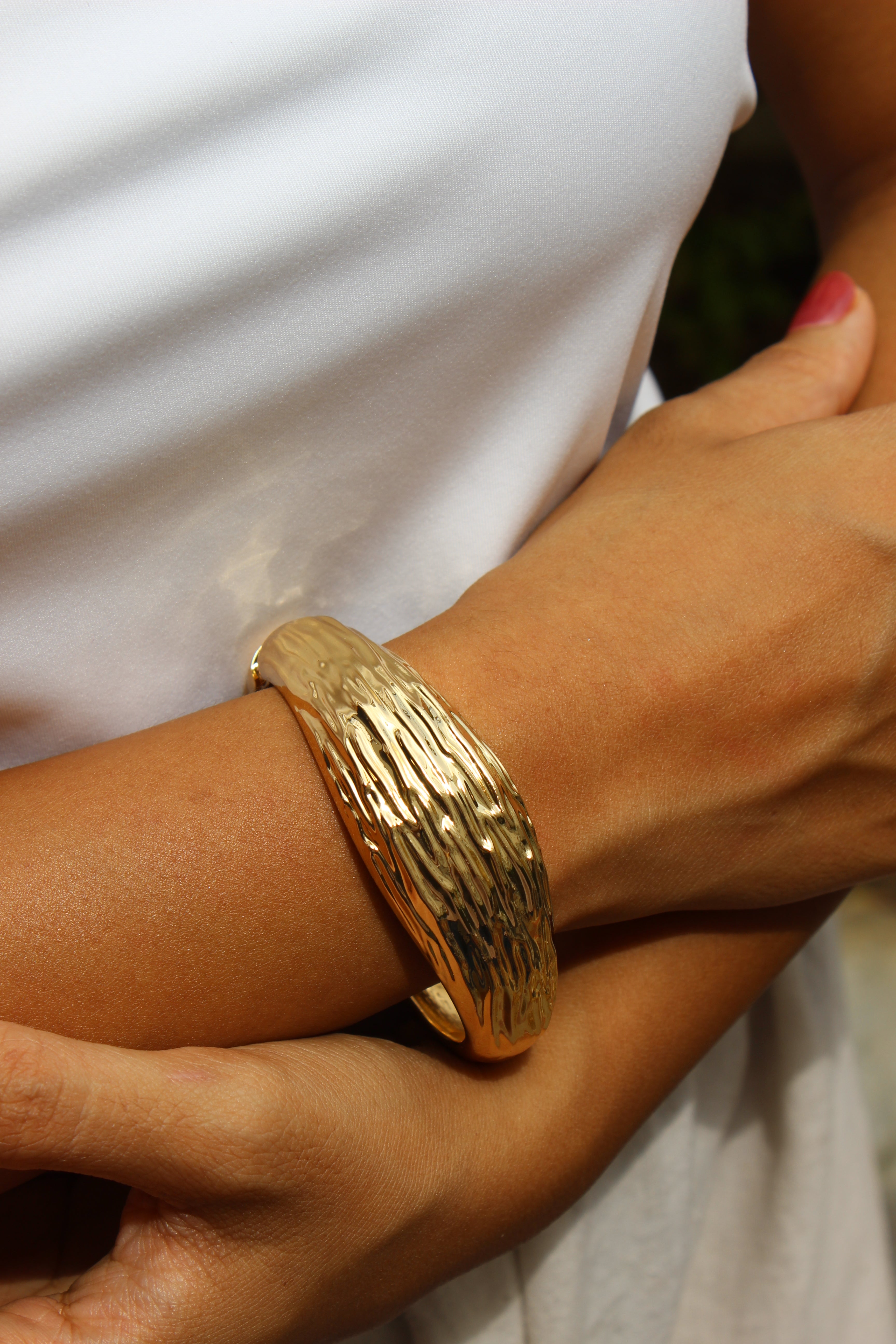 Gold Yara bangle bracelet worn on model’s wrist 