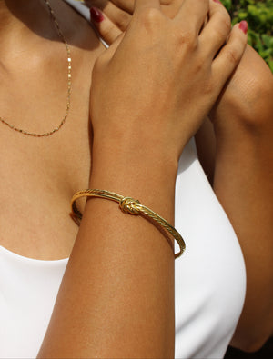 Close-up of a model's wrist wearing a Knota Cuff Bracelet with a blurred background