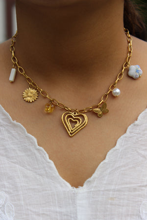 Hearts in Bloom Charms Necklace on a model's neck against a white fabric background