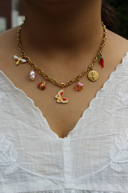Close-up of model’s neck showcasing gold charm necklace with nature-inspired pendants