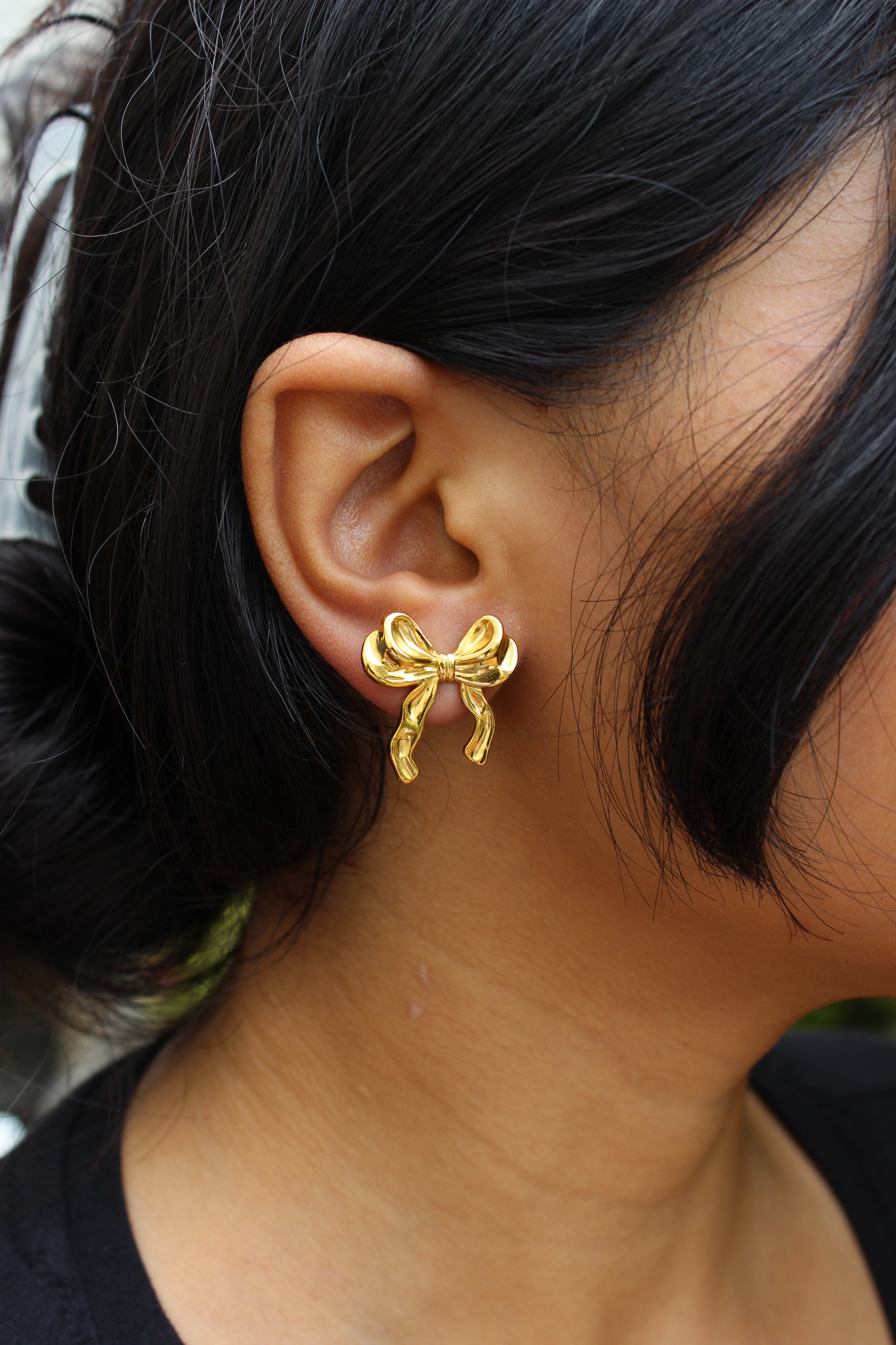 Goldtie Stud Earrings earring worn by a model with dark hair