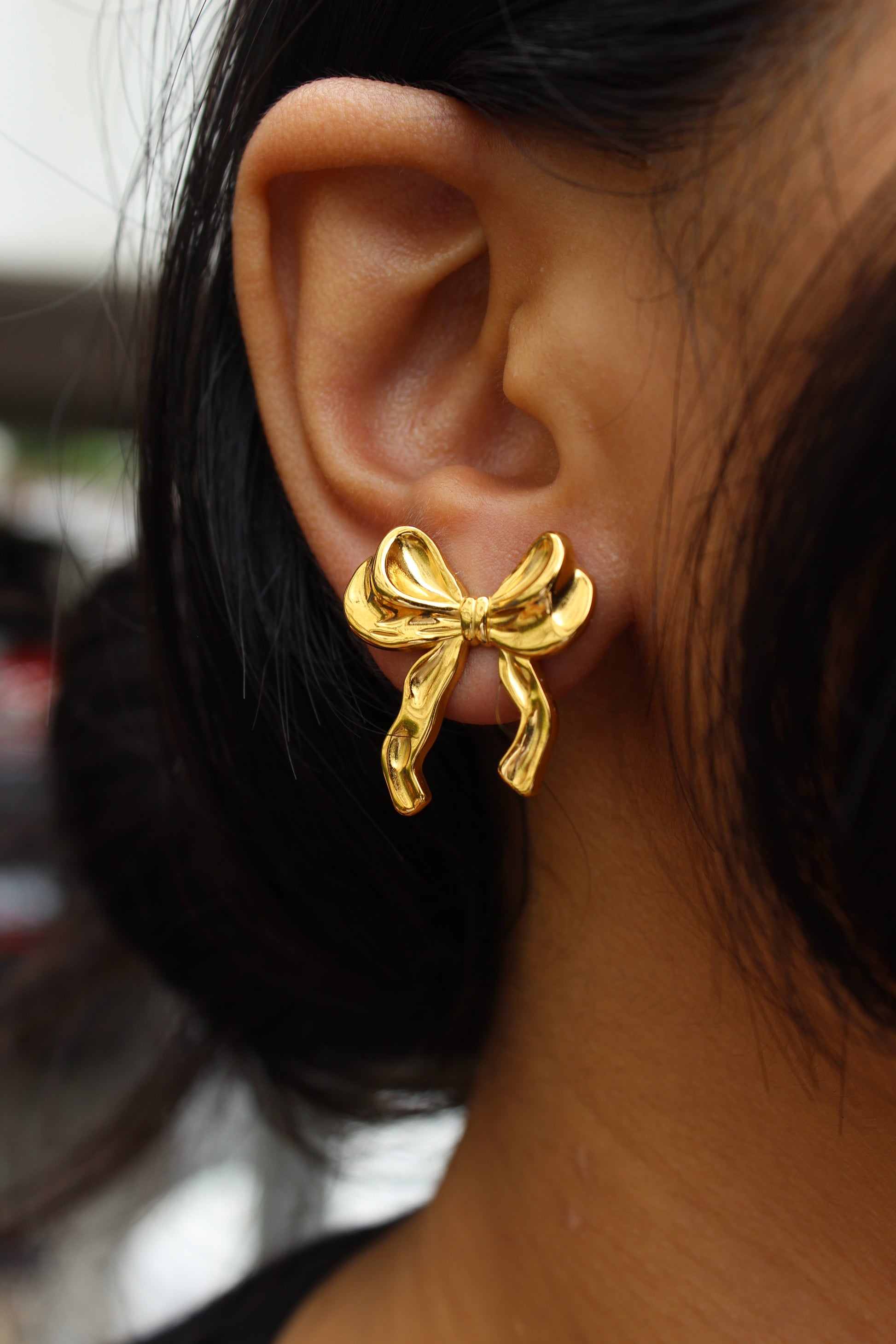 Goldtie Stud Earrings worn by a model with blurred background