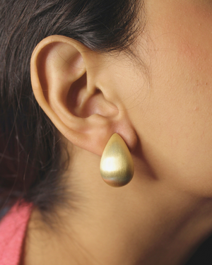 Gilded Weave Hoop Earrings on an ear with a blurred background