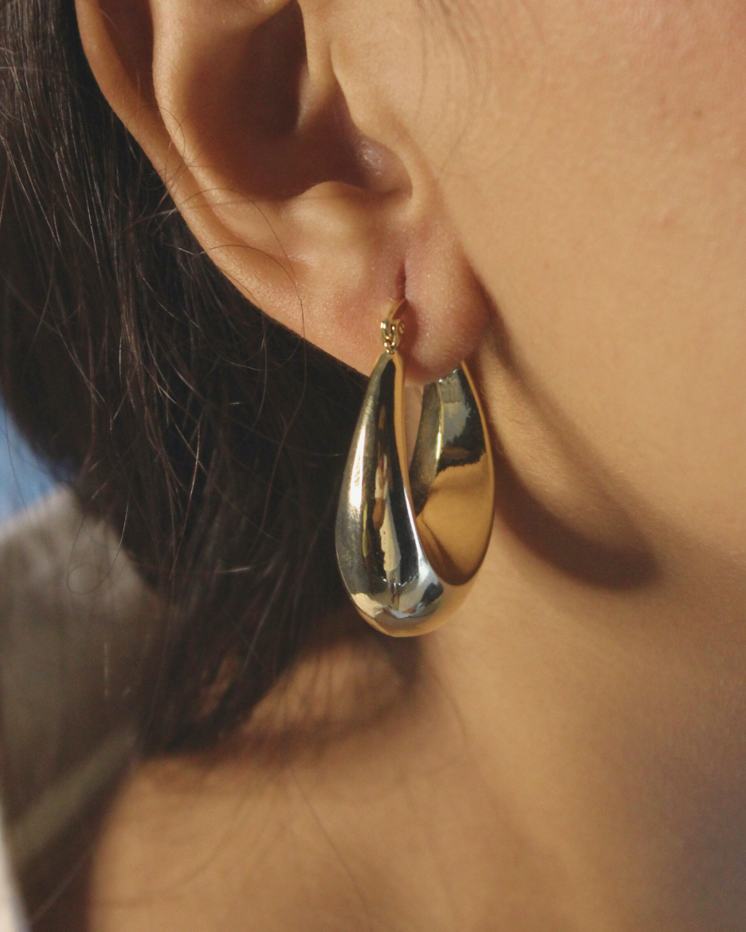 Solara Hoop Earrings worn by a model with a blurred background
